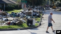 A resident walks past debris in a neighborhood that was flooded by Hurricane Harvey in Beaumont, Texas, Sept. 26, 2017.