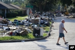 FILE - A resident walks past debris in a neighborhood that was flooded by Hurricane Harvey in Beaumont, Texas, Sept. 26, 2017.