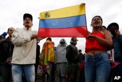 Venezuelan migrants protest the creation of a new, government-organized camp, which migrants can move to voluntarily, as they stand outside their current tent city near the main bus terminal in Bogota, Colombia, Nov. 13, 2018.
