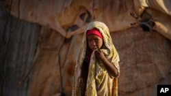 A young Somali girl stands outside her makeshift hut at a camp in Qardho, Somalia, March 9, 2017.