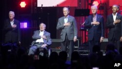 Former Presidents from right, Barack Obama, Bill Clinton, George W. Bush, George H.W. Bush and Jimmy Carter place their hands on their heart for the national anthem at the opening of a hurricanes relief concert in College Station, Texas, Oct. 21, 2017. All five former U.S. presidents joined to support a Texas concert raising money for relief efforts from Hurricane Harvey, Irma and Maria's devastation.