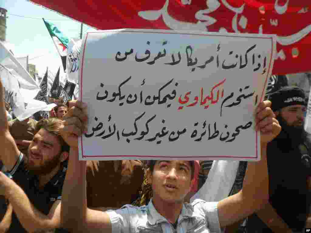 This image provided by ENN shows a protester with a sign reading &quot;If America does not know who used the chemical weapons, so it could be flying saucers from another planet,&quot; Sarmada, Idlib, Syria, May 3, 2013.