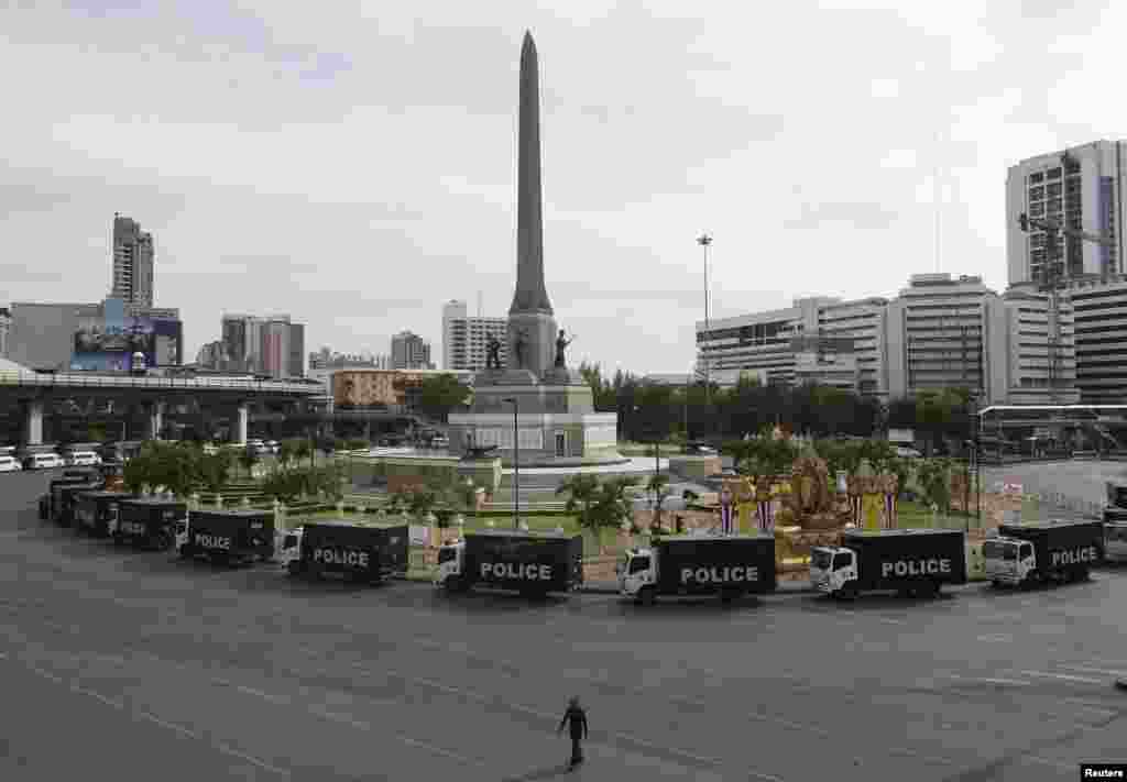 A man walks near police vehicles at an empty Victory Monument, where anti-coup protesters were gathering on previous days, in Bangkok, May 29, 2014.