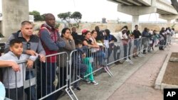 En esta foto de archivo del 26 de septiembre de 2019, solicitantes de asilo en Tijuana, México, escuchan los nombres que se llaman de una lista de espera para solicitar asilo en un cruce fronterizo en San Diego.