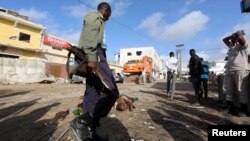 Un soldat somalien gardent les corps des victimes de l'attaque à la voiture piégée revendiquée par les shebab près de l'hôtel Nasahablood à Mogadiscio en Somalie, le 26 juin 2016.