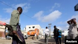 Un soldat somalien gardent les corps des victimes de l'attaque à la voiture piégée revendiquée par les shebab près de l'hôtel Nasahablood à Mogadiscio en Somalie, le 26 juin 2016.