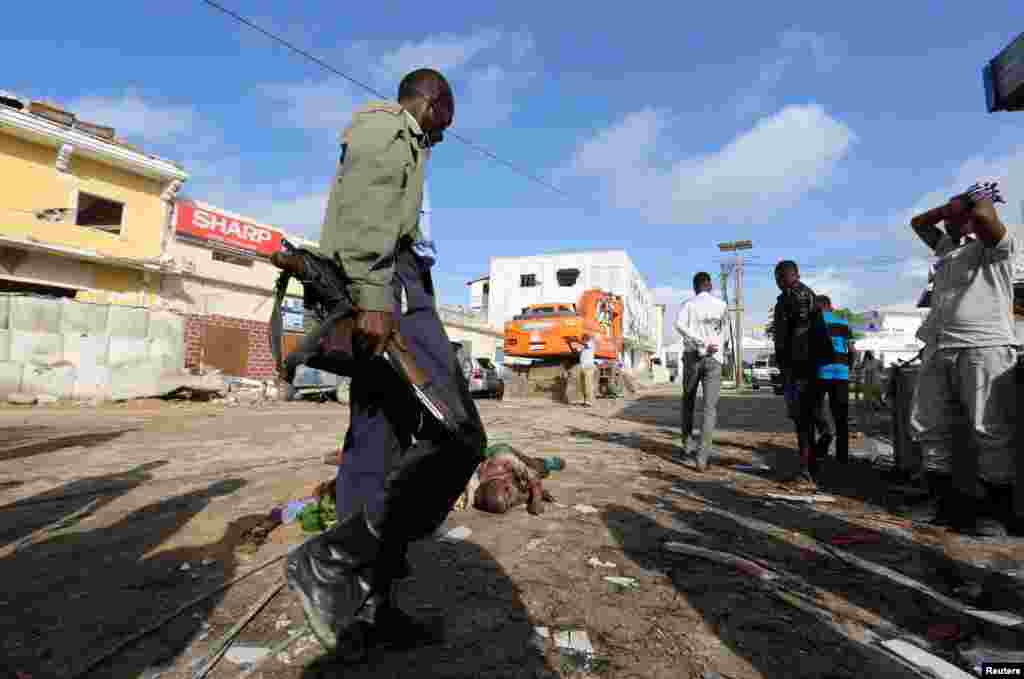 Un soldat somalien gardent les corps des victimes de l'attaque à la voiture piégée revendiquée par les shebab près de l'hôtel Nasahablood à Mogadiscio en Somalie, le 26 juin 2016.