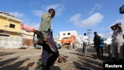 Un soldat somalien gardent les corps des victimes de l'attaque à la voiture piégée revendiquée par les shebab près de l'hôtel Nasahablood à Mogadiscio en Somalie, le 26 juin 2016.