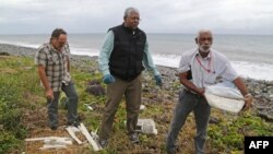 Un expert malais, au centre, examine des fragements de l'avion de Malyasia Airlines qui assurait le vol MH370 sur une plage à Saint-Andre de la Reunion,4 aout 2015.