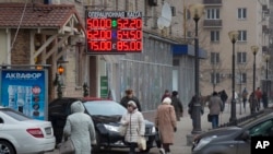 FILE - People walk past a currency exchange rate display in central Moscow, Dec. 1, 2014.