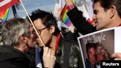 Engaged couple Mark Nomadiou (L) and Wyatt Tan (2nd L) share a kiss as friend Michael Walsh (R) looks on as they protest against the Defense of Marriage Act in front of the U.S. Supreme Court in Washington, March 27, 2013. For the second day running, the 