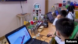 North Korean students learn and engage with a robot in Pyongyang, North Korea November 3, 2021, in this still image obtained from Reuters. (REUTERS TV/KRT)