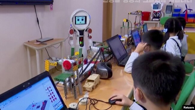 North Korean students learn and engage with a robot in Pyongyang, North Korea November 3, 2021, in this still image obtained from Reuters. (REUTERS TV/KRT)