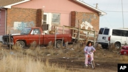 A Lakota girl rides her bike on Pine Ridge, the Indian reservation closest to Rapid City, S.D., on Tuesday , Jan. 10, 2006. At least 60% of Pine Ridge homes are substandard, and 30% of citizens are homeless. Photo: AP/Johnny Sunby
