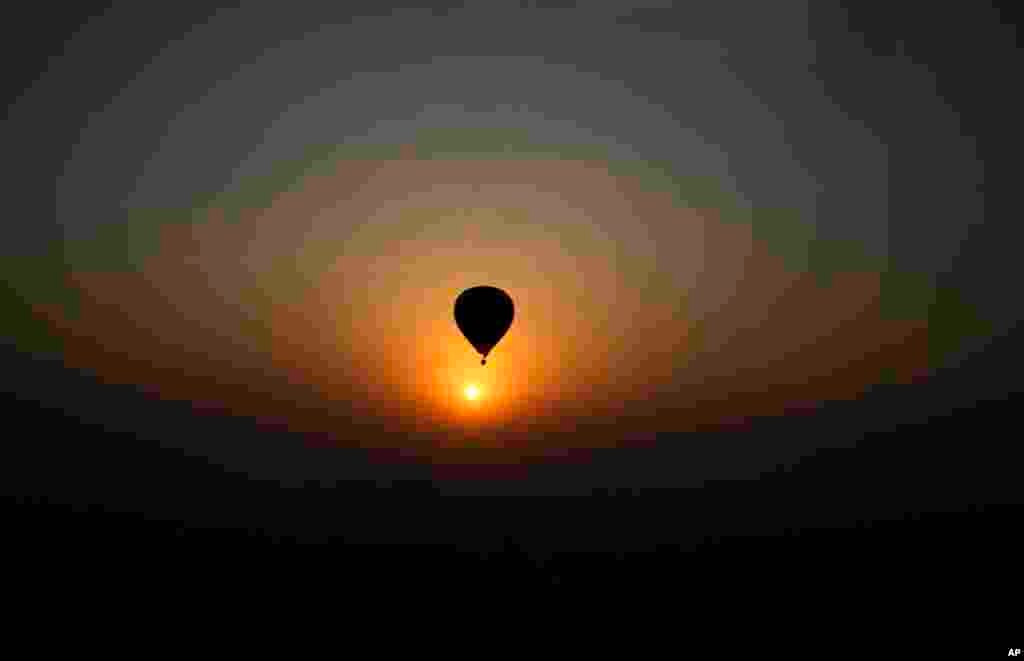 A hot-air balloon flies against a sunrise during Lucknow Balloon Festival in Lucknow, India.