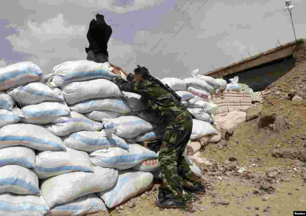 A Free Syrian Army fighter stands behind a pile of sandbags in Raqqa province, east Syria, May 6, 2013.