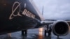 A worker walks past an engine on a Boeing 737 MAX 8 airplane being built for American Airlines at Boeing Co.'s Renton assembly plant, March 13, 2019, in Renton, Wash.