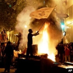 An Occupy Oakland protester waves a flag next to a bonfire in Oakland, California, November 3, 2011.