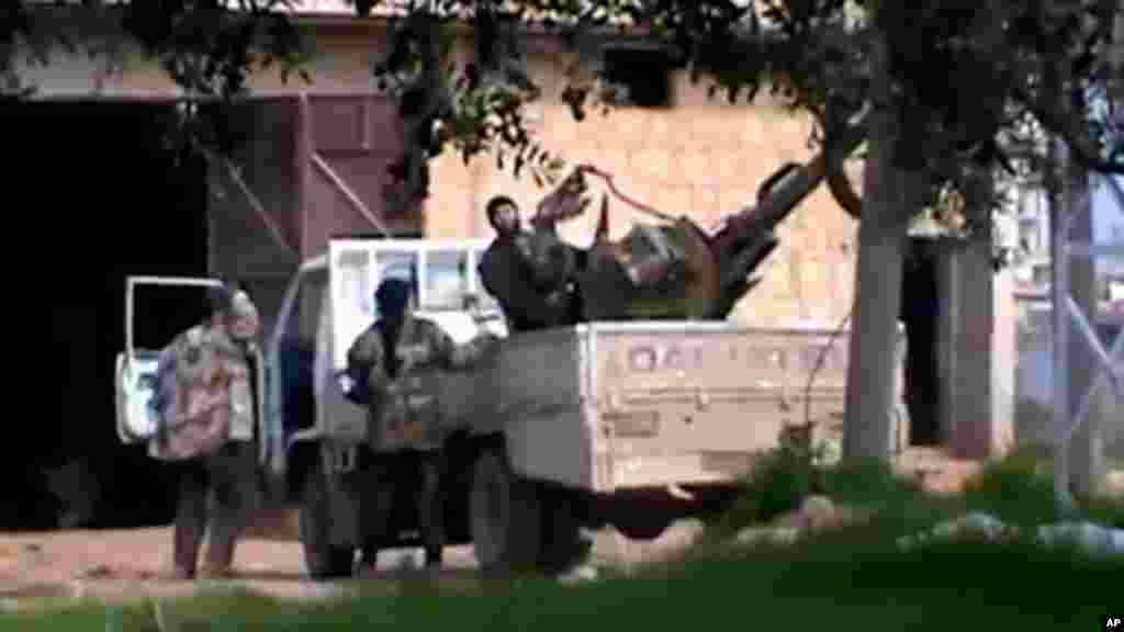 In this image taken from video obtained from the Shaam News Network, which has been authenticated based on its contents and other AP reporting, A Free Syrian Army fighter stands on a vehicle as he holds his weapon in Taftanaz village, Idlib province, nort