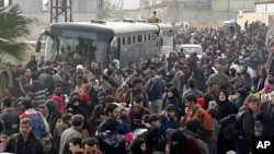 This photo released by the Syrian official news agency SANA, shows Syrian civilians with their belongings, fleeing from fighting between the Syrian government forces and rebels, in eastern Ghouta, a suburb of Damascus, Syria, March. 15, 2018. 