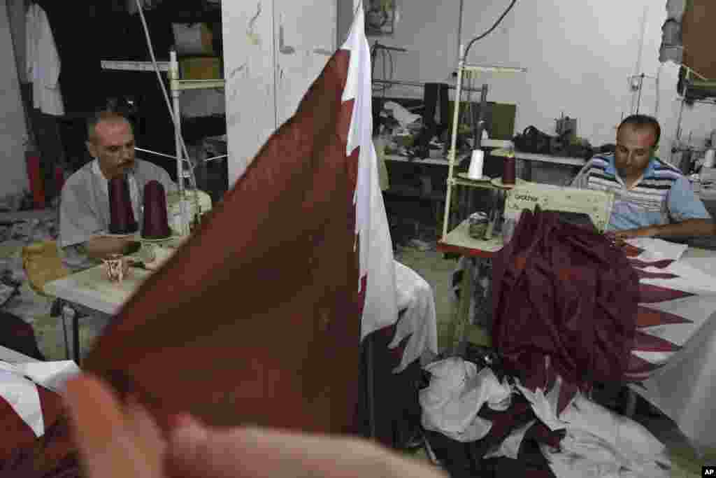 ນັກຕັດຫຍິບປາແລັສຕາຍ Eyad Absi (ຊ້າຍ) ແລະ Salama Ashour (ຂວາ) ເຮັດທຸງຂອງກາຕາ ໃນຮ້ານ ເພື່ອຕ້ອນຮັບການຢ້ຽມຢາມຢ່າງເປັນທາງການຂອງ ກະສັດ Sheik Hamad bin Khalifa al-Thani ຂອງກາຕາ ໃນເຂດກາຊາ, ໃນວັນທີ 21 ຕຸລາ, 2012.