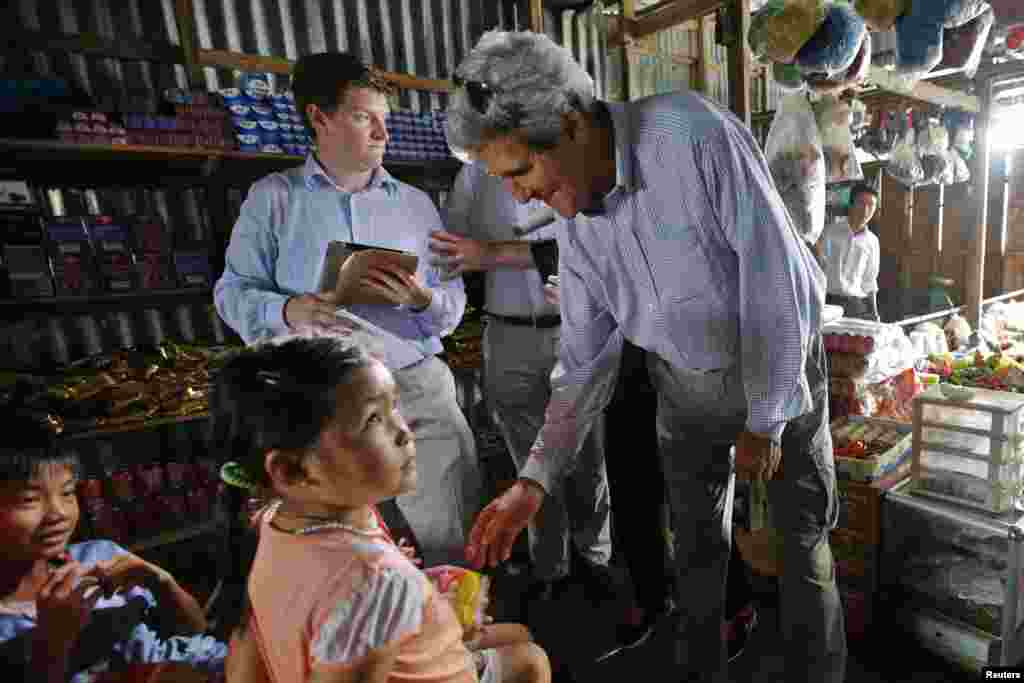 Menteri Luar Negeri Amerika John Kerry memberikan sekantong kue coklat pada anak-anak di sebuah toko di sepanjang delta sungai Mekong, 15 Desember 2013.