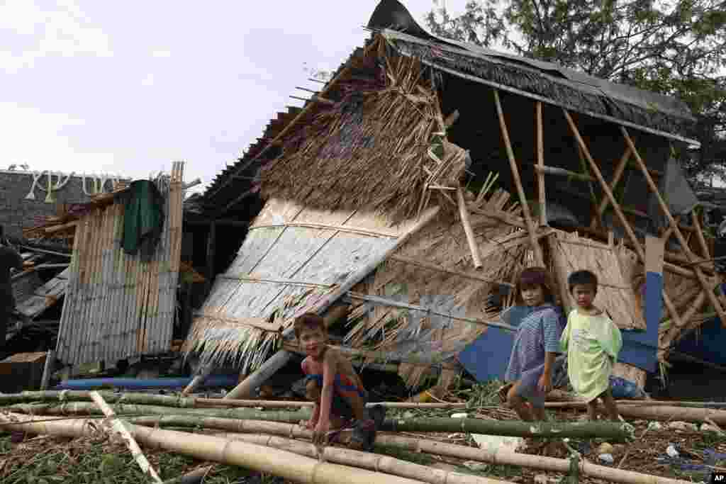 Children play near a damaged house at the coastal village of Bajaoan, at Batangas city, Philippines Thursday, July 17, 2014.