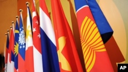 Bendera ASEAN, kanan, memimpin bendera 10 negara anggota selama pertemuan Forum Regional ASEAN di Singapura.