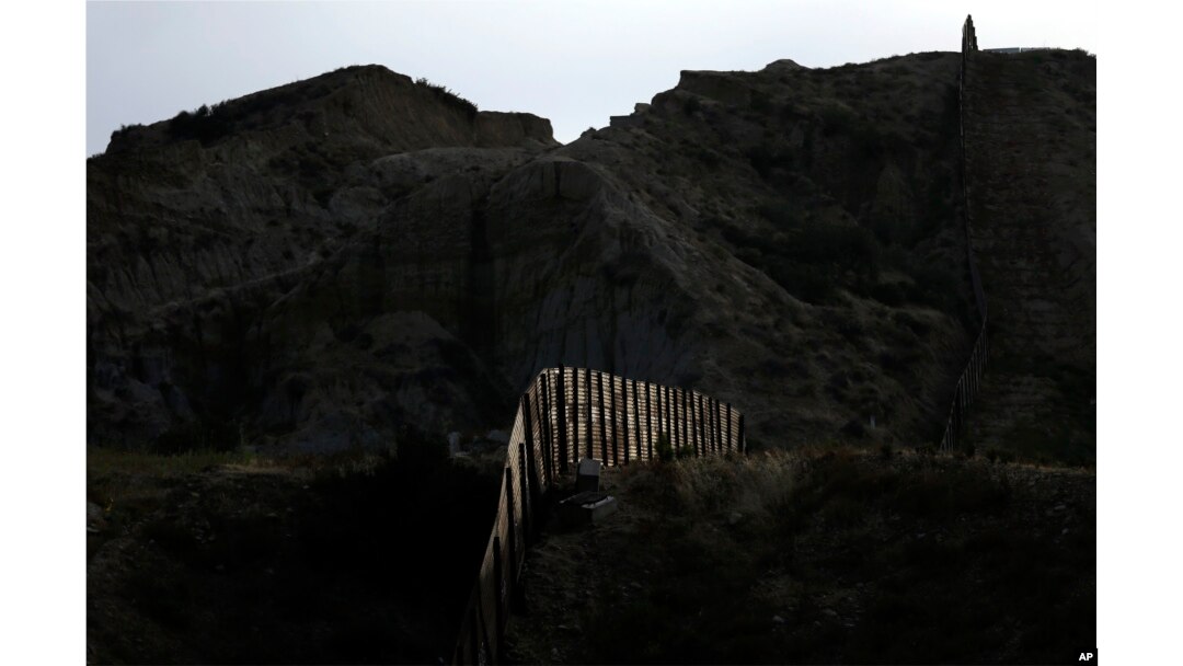 FILE - Light illuminates a section of the primary fence separating Tijuana, Mexico, and San Diego on June 22, 2016. An estimated 40 percent of the 11.4 million people in the U.S. illegally overstayed visas, a crucial but often overlooked fact in the immigration debate.