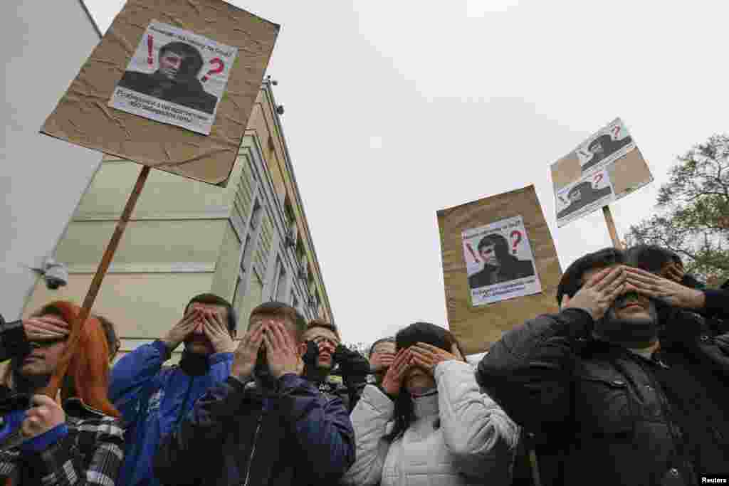 Activistas tapam os olhos e levantam cartazes com fotos do ministro ucraniano do Interior, Arsen Avakov, durante uma manifestação na sede do ministério, em Kiev, Abril 14, 2014.