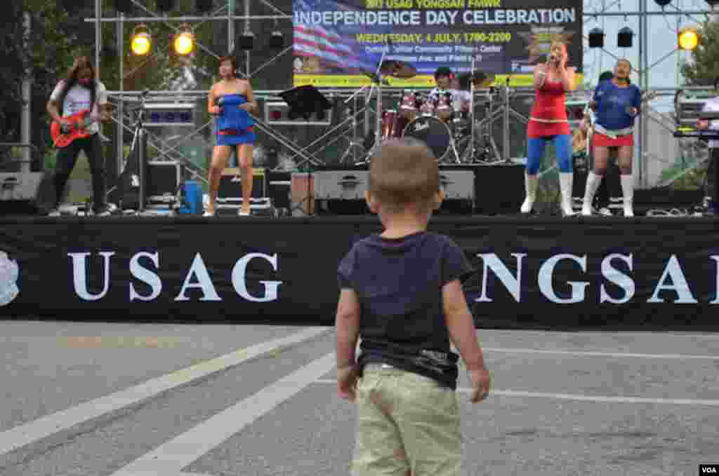 Ayden Massey, anak berumur 19 bulan dari Seoul, menyaksikan band &quot;Absolute&quot; dari Filipina yang ikut tampil dalam Perayaan 4 Juli di Barak Tentara Amerika di Garrison-Yongsan, Korea Selatan, 4 JUli 2012 (S.L. Herman/VOA).