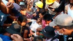 FILE - Anti-coup protesters surround an injured man in Hlaing Thar Yar township in Yangon, Myanmar, March 14, 2021. 