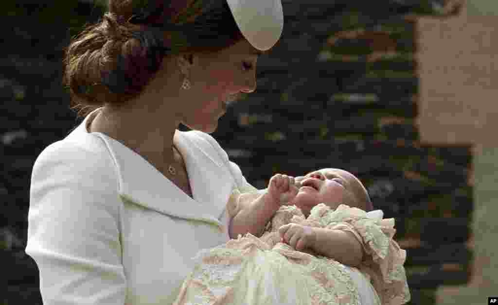 Britain's Kate the Duchess of Cambridge carries Princess Charlotte after taking her out of a pram as they arrive for Charlotte's Christening at St. Mary Magdalene Church in Sandringham, England.