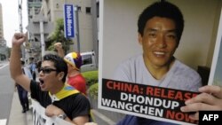 FILE - Protesters of "Students for a Free Tibet Japan" shout slogans during a demonstration to demand the release of arrested Tibetan filmmaker Dhondup Wangchen, who is pictured on the poster, in front of the Chinese Embassy in Tokyo, Aug. 1, 2009. Wangchen, jailed in China in March 2008, escaped from Tibet and joined his wife and four children in San Francisco on Dec. 25, 2017. 