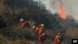 Firefighters work to remove brush to prevent a wildfire from spreading along a remote oil field access road in Ventura County, California, Dec. 26, 2015.