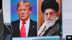 FILE - A man walks by a huge screen showing then-President Donald Trump, left, and Iranian Supreme Leader Ayatollah Ali Khamenei, in Tokyo, Jan. 8, 2020.