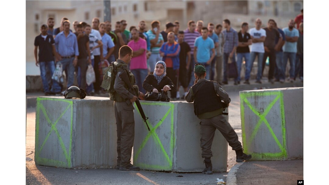 Israeli border police check Palestinian's IDs at a checkpoint as they exit the Arab neighborhood of Issawiyeh in Jerusalem, Oct. 18, 2015.