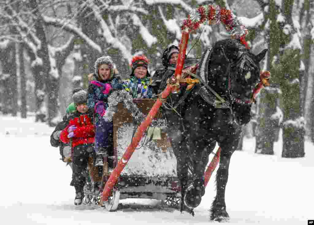 Children ride a horse sleigh in snowfall in a park in Pavlovsk, outside St.Petersburg, Russia, Dec. 23, 2018.