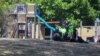 This photo taken and provided on Dec. 17, 2021 by ACM shows members of the local police reacting near a playground outside the Hillcrest Primary School the day after five children died and four others were injured when a bouncy castle was blown into the air in the Tasmania.