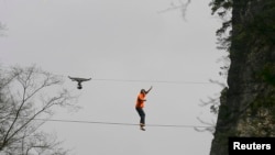 FILE - American climber Dean Potter walks barefoot on a rope which is connected between two mountain peaks in Enshi, Hubei province, April 22, 2012.