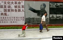 在中国广东省汕头的文革博物馆，参观者在中共前领导人毛泽东在文革期间的照片前面走过 （2006年5月15日）毛泽东所说他一生所做两件大事之一的文革，被中共中央彻底否定。
