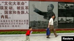 参观者走过广东省汕头的文革博物馆印有中共前领导人毛泽东在文革期间照片的招贴画 （2006年5月15日）