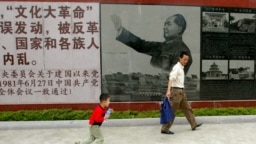 参观者走过广东省汕头的文革博物馆印有中共前领导人毛泽东在文革期间照片的招贴画 （2006年5月15日）