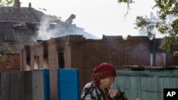 Seorang warga melewati sebuah rumah yang hancur di Semyonovka, sebuah kota kecil dekat Slovyansk, Ukraina (23/5).