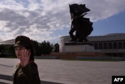 A uniformed tour guide gestures to tourists outside the War Museum in Pyongyang, North Korea, Oct. 9, 2015.