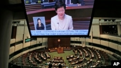Chief Secretary Carrie Lam is seen on a TV screen as she unveils the Beijing-backed election reform package’s details at the legislative chamber in Hong Kong, April 22, 2015. 