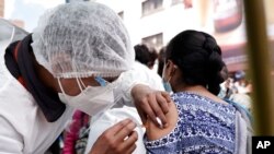 Un trabajador de salud aplica a una mujer la primera dosis de la vacuna Sinopharm fuera de la iglesia Monte de Oración en La Paz, el martes 28 de diciembre de 2021.