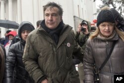 Former Georgian president Mikheil Saakashvili, left, and his wife Sandra Roelofs, right, attend a rally of his supporters as they camp out outside parliament demanding the resignation of the Ukrainian president, in Kyiv, Dec. 6, 2017.