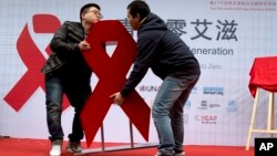 Men move a red ribbon display at an event to promote awareness of HIV testing ahead of the December 1 World AIDS Day, in Beijing, China, Nov. 27, 2014.