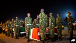 Military pallbearers stand to attention next to the coffins of four Kenyan soldiers who were killed in Somalia, at a ceremony to receive their bodies which were airlifted to Wilson Airport in Nairobi, Kenya Monday, Jan. 18, 2016.